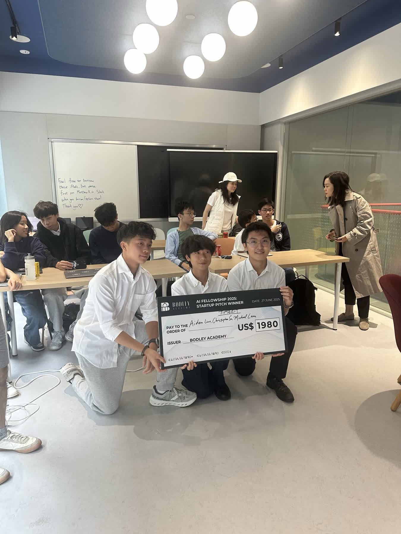 A previous cohort's winning team holding their startup-pitch prize cheque